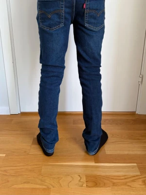 Mörkblå slim fit jeans - Levi’s - Säljer ett par mörkblå slim fit jeans från Levi’s Modell Slim Taper med klassisk femficksdesign och kontrastsömmar. Jeansen har normal midja och raka ben, perfekta för en avslappnad men ändå snygg look. Materialet är mjukt denim som sitter skönt hela dagen.