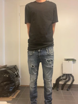 Replay jeans med slitningar - Säljer ett par blå jeans med slitningar och hål på både fram- och baksida. Jeansen har en tvättad look, raka ben och klassiska fem fickor. Perfekta för dig som gillar en avslappnad och trendig stil. Stolrek 28/30 fint skick!