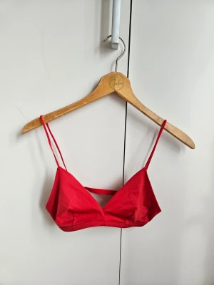 Weekday - röd trekantsbikinitopp med smala band - Enkel och snygg röd bikinitopp med trekantsformade kupor och tunna axelband. Modellen har en minimalistisk design och är tillverkad i ett stretchigt material som ger en bekväm passform. Perfekt för strandhäng eller pooldagar.