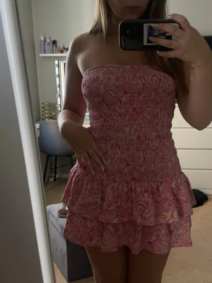 Rosa bandeau kortklänning med volang - Supersöt bandeauklänning i rosa med ljusgult mönster, använd till ett tillfälle. 