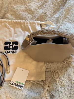 GANNI mini bou bag - Oyster Gray  - GANNI väska i färgen oyster gray, som inte längre säljs eller tillverkas <3  - Ingår: dustbag, tillkommande band, original prislapp   - Skick: nyskick, använd enstaka gång   - Yttermaterial: 65% återvunnet läder, 19% polyuretanfiber, 16% polyester  - Innerfoder: 65% återvunnen bomull, 35% bomull  - Mått: höjd 11 cm, bredd: 25 cm, djup : 11,5 cm, längd på axelremmen: 50 cm (justerbar och avtagbar)  - Nypris: 3595 SEK / 345 €