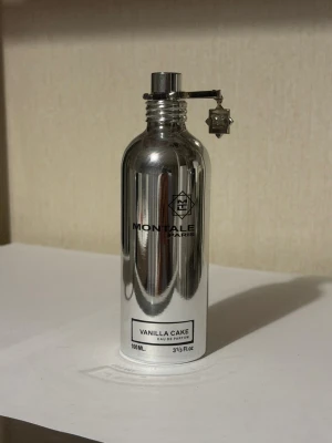 Montale Vanilla Cake parfym 100ml - Montale Vanilla Cake är en parfym i en spegelblank, silverfärgad metallflaska med svart text och en unik charm vid korken. Doften är söt och gourmand med tydlig vaniljkaraktär. Flaskan rymmer 100 ml och har en modern, stilren design.