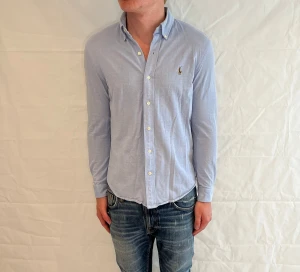Polo Ralph Lauren Knit Oxford Shirt Light Blue - Ljusrblå oxfordskjorta i 100% bomull, begagnad i mycket gott skick.