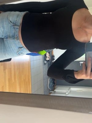 Svart långärmad topp med rund hals - En stilren svart långärmad topp med rundad, djup urringning och slits i ärmen. Sitter tight och har en enkel, clean look som passar till allt. Tillverkad i mjukt material som känns skönt mot huden. Perfekt att matcha med jeans eller kjol.