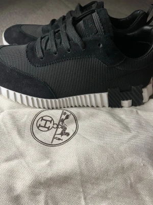 Hs Sko - Snygga svarta sneakers med ovandel i textil och mockadetaljer. Skorna har en chunky, räfflad vit sula med svarta detaljer på sidan. Klassisk snörning och låg profil som passar till många olika stilar.