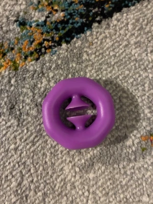 Lila åttakantig plastpryl - En lila åttakantig plastpryl med två konformade piggar i mitten. Snapper fidget toy. De klickande ljudet kan ge lugn.