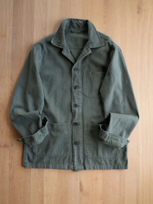 Green Chore Jacket, size S - Snygg olivgrön overshirt i kraftigt bomullstyg med ståkrage och knäppning framtill. Tre stora fickor framtill ger en cool workwear-känsla. Perfekt lager-på-lager-plagg för dig som gillar stilren och avslappnad look.