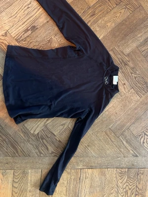 Svart långärmad ridtröja från CRW  - Snygg svart långärmad topp från CRW med hög krage och ett bett som detalj vid halsen. Tillverkad i mjukt och stretchigt material som passar perfekt till träning eller chill. Enkel och stilren design som funkar till det mesta.