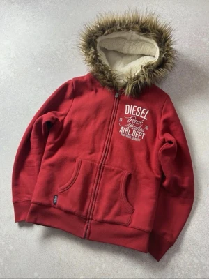 Röd hoodie med päls från Diesel - Riktigt schysst röd zip up från Diesel. Varmt material på insidan och päls eunt luvan. Funkar svin bra på en kall morgon eller om du vill se lite schysstare ut.