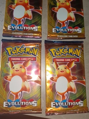 Pokémon Evolutions boosterpaket x4 - Fyra oöppnade Pokémon Evolutions boosterpaket med Raichu på framsidan. Varje paket innehåller 10 samlarkort och har en glansig, färgglad förpackning i guld, orange och blått. Perfekt för dig som vill utöka din samling eller jaga efter sällsynta kort.