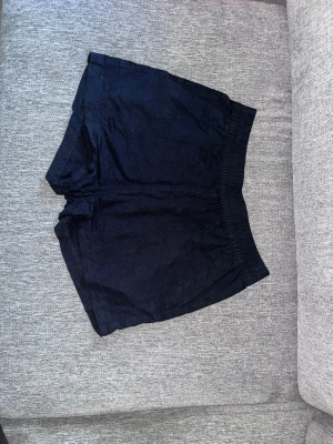 Svarta shorts i bomull XS - Säljer ett par svarta shorts i mjuk bomull med elastisk midja. De har en enkel och avslappnad design, perfekta för varma dagar. Passar dig som gillar basic och bekvämt.