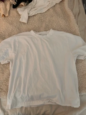 Vit baggy t-shirt i bomull - Enkel och stilren baggy vit t-shirt i mjuk bomull. Klassisk passform med rund hals och korta ärmar. Perfekt att matcha med jeans eller shorts för en clean look.