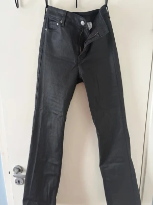 Svarta bootcut jeans från &Denim - Snygga svarta bootcut jeans från &Denim med slim fit och hög midja. Jeansen har klassisk femficksdesign och dragkedja med knapp. Perfekta för dig som gillar en stilren och trendig look.