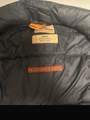 Svart dunväst Parajumpers - Säljer en svart dunväst från Parajumpers Masterpiece Series i storlek Small men passar även M. Västen har flera fickor med dragkedja och knapp, samt detaljer i orange och gul. Tillverkad i slitstarkt material och fodrad med dun för extra värme.