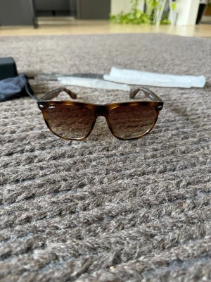 Bruna solglasögon från ONEWear - Snygga solglasögon från ONEWear med bruna bågar och tonade linser. Klassisk rektangulär form som passar till de flesta stilar. Kommer med originalfodral och putsduk. Perfekta för soliga dagar och ger en cool vibe till din outfit.