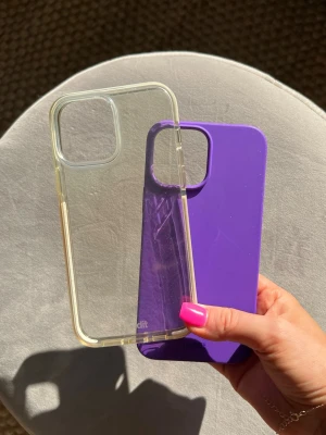2st mobilskal från Holdit, iPhone 13 Pro Max - Två mobilskal från Holdit till iPhone 13 Pro Max.   Kompabilitet: iPhone 13 Pro Max.  Säljanledning: Kommer ej till användning.  Brister: Den lila har en spricka på insidan, men det syns ej från utsidan. Den genomskinliga är lite gulnad.  Material: Silikon, plast.