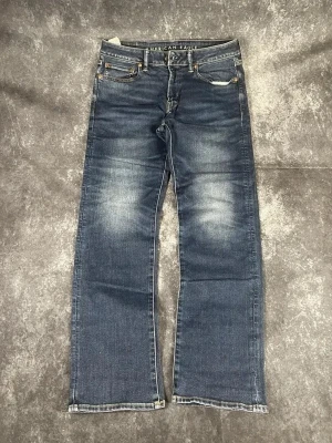 Blå American Eagle vintagejeans för herrar i storlek W31 L34 - Avslappnad och bekväm passform, slitstarkt denimtyg och utmärkta som vardagsjeans.  Skick: 9,5/10  Midja: 43 cm Benslut: 22 cm Lår: 31 cm Totallängd: 109 cm Måtten finns även på bilderna  Skickas inom ett dygn På min profil finns fler jeans. A86