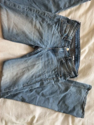 Bootcut ljusblå jeans low waist - Säljer ett par ljusblå bootcut jeans med låg midja från H&M. Klassisk femficksmodell i stretchig denim med snygga sömmar och lätt slitning framtill. Perfekta för dig som gillar en avslappnad men trendig look.