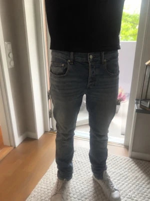  jeans herr - riktigt snygga Sandro slim fit jeans med klassisk femficksdesign och knappgylf. Jeansen har en tvättad och sliten look med ljusa partier och raka ben. Perfekta för en avslappnad stil och passar till det mesta i garderoben.