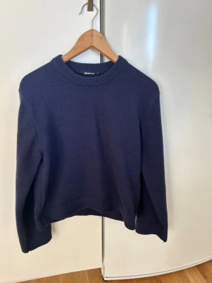 Mörkblå stickad tröja Gina Tricot - Mysig mörkblå stickad tröja från Gina Tricot med rund halsringning och ribbade muddar vid ärmslut och nederkant. Perfekt för lager på lager och enkel att matcha till olika outfits. Klassisk modell med avslappnad passform.