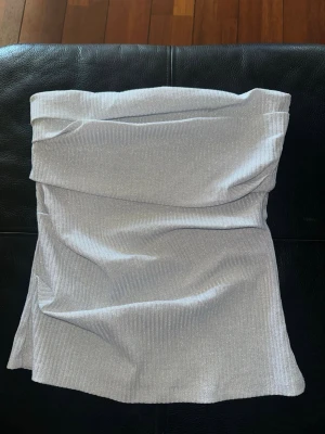 Glittrig silver tubtopp - Snygg glittrig silver tubtopp med bandeau-modell från Zara i storlek M. Tyget har en lätt ribbad struktur och skimrar i ljuset. Använd en gång endast🪩🩶