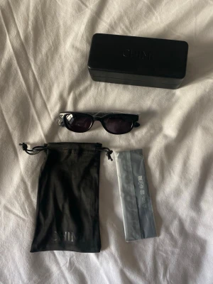 Svarta Lyra solglasögon från Chimi - Nypris 1800kr - Snygga svarta solglasögon från Chimi, modell Lyra. Rektangulär form med mörka glas. Kommer med originalfodral, putsduk och tygpåse. Perfekta för dig som vill ha en stilren och modern look.