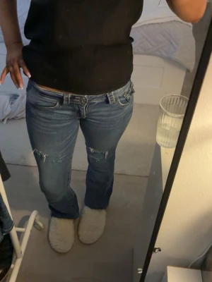 Blå bootcut jeans med slitningar - Säljer ett par blå bootcut jeans med slitningar. HAR GJORT HÅLEN SJÄLV!!!!