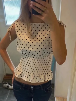 Prickig vit topp - Så fin vit topp med prickar o smockad midja! Väldigt populär och helt nytt skick💞