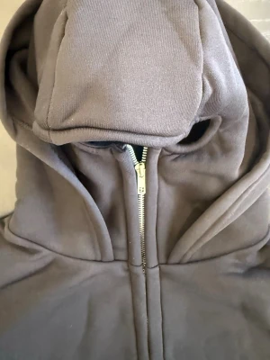 Svart balaclava hoodie – streetwear (M/L) - Stilren svart hoodie med inbyggd balaclava (baklava) som ger en unik och trendig streetwear-look. Perfekt för kallare dagar och för dig som vill sticka ut med en edgy stil.  Detaljer: 	•	Inbyggd balaclava/huva 	•	Klassisk svart färg 	•	Bekväm passform 	•	Mjuk och varm 	•	Perfekt för höst och vinter  Storlek: Passar M–L  En hoodie som kombinerar stil och funktion – både praktisk och trendig.  💬 Hör av dig vid intresse!