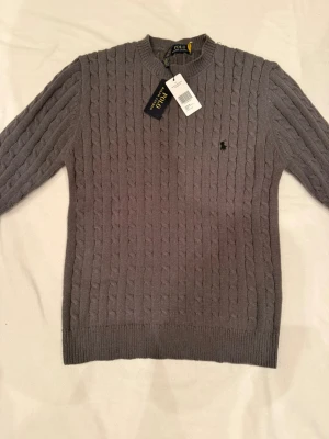 Grå Ralp Lauren Tröja - Snygg grå kabelstickad tröja från Ralp Lauren.Helt ny 