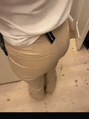Beige byxor - Säljer ett par snygga beige byxor. De har hög midja, tight passform och bakfickor som ger en schysst siluett. Materialet är mjukt, perfekt för en trendig och bekväm look.