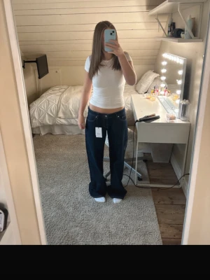 Mörkblåa raka jeans med låg midja - Säljer ett par mörkblåa jeans med rak passform och låg midja. Jeansen har klassiska fem fickor och vita sömmar som kontrast. Perfekta för en avslappnad och trendig look. Passar mig som är 170cm. Hör av er vid fler frågor💕💕