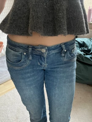 Blå low waist jeans från LTB - Säljer ett par blå low waist jeans från LTB med klassisk femficksmodell och raka ben. Jeansen har snygg tvättad look och silverfärgade knappar. Perfekta för dig som gillar en avslappnad och trendig stil. Storlek: w26 L34 längd: 84 midja:38