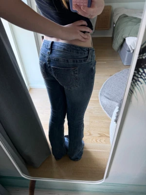 True Religion lågmidjade bootcut - Snygga blå bootcut jeans med låg midja och dubbla knappar fram. Jeansen har klassiska fickor både fram och bak samt en lätt tvättad look. Perfekta för en avslappnad och trendig stil. Kan sänka pris vid snabb affär.
