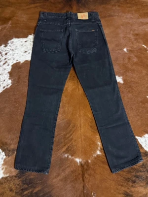Nudie LowSlimJim Black Black - Tjena! Säljer dessa riktigt snygga vintage nudies ifrån tidigt 2000tal, modellen är LowSlimJim och sitter som W31/L30 men går enkelt att förlänga om du kollar bild 7, fint skick, hör av dig vid funderingar!🙌