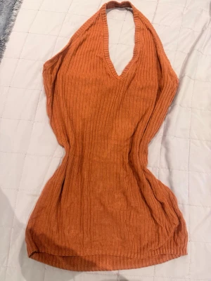 Ribbad orange halterneck topp - Trendig ribbad halterneck topp i orange med djup v-ringning. Toppen är ärmlös och har en figurnära passform, perfekt för att skapa en snygg och avslappnad look. Materialet känns mjukt och stretchigt.