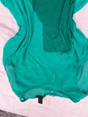 Turkos mesh body - Säljer en turkos body i meshmaterial med rund halsringning och tryckknappar i grenen. Bodyn har transparenta partier och är stretchig för en bekväm passform. Perfekt att styla med jeans eller kjol för en trendig look.