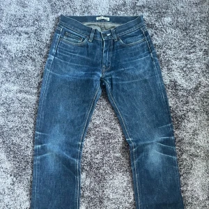 Raw denim jeans från Acne - Säljer ett par raw denim jeans från Acne. Jeansen har snygga slitningar och kontrastsömmar, tillverkade i denim av bomull. Perfekta för en avslappnad och trendig look.