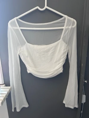 Vit mesh långärmad topp - Säljer en vit mesh topp med långa ärmar och fyrkantig urringning. Toppen är lätt transparent med ett dubbelt tyg över bysten och har en croppad passform. 