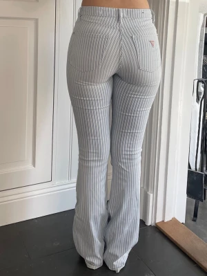 Blåvit randiga bootcut jeans Guess - Snygga blåvit randiga jeans från Guess med bootcut passform. storlek 27