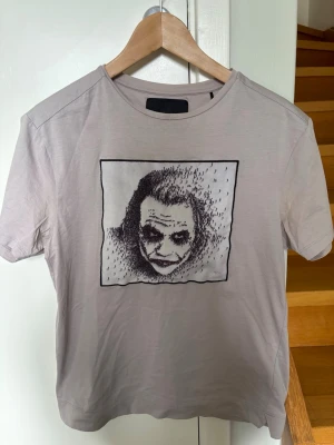 LIMITATO ljusgrå t-shirt med tryck - Snygg ljusgrå t-shirt från LIMITATO med ett unikt svartvitt tryck på bröstet. T-shirten har rund hals och korta ärmar, tillverkad i mjuk bomull som känns skön mot huden.