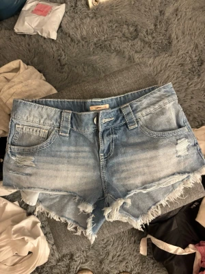 Ljusblå jeansshorts med fransar - Köpte nya med prislapp på vinted, men har aldrig använt passar mellan XS-S säkert M med. Finns en pytte liten fläck som syns på sista bilden men var där när jag köpte dom