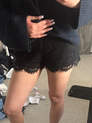 Svarta spets-shorts från Gina Tricot - Säljer ett par svarta shorts från Gina Tricot med snygg spetsdetalj och blommigt mönster. De är midwaist och har vågig spetskant nertill. Hör av er om ni har frågor💕