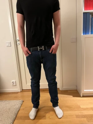 Mörkblå slim fit jeans från LEE - Snygga mörkblå slim fit jeans från Lee med klassisk femficksdesign och normal midja. Jeansen har en stilren look och passar perfekt till en avslappnad stil. Tillverkade i denim med lätt stretch för extra komfort.