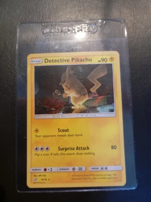 Detective Pikachu Pokémonkort - Unikt Detective Pikachu samlarkort från Pokémon-serien. Kortet har gul ram och motiv av Pikachu med förstoringsglas. Kortet är på engelska och ligger i ett genomskinligt plastfodral. Perfekt för samlare eller Pokémonfans.