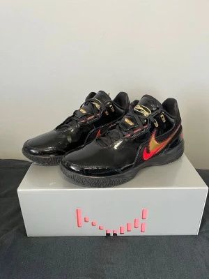 Nike LeBron NXXT Gen AMPD – Black / University Red / Gold – Strl 46 - Beskrivning: Säljer ett par Nike Nike Zoom LeBron NXXT Gen AMPD i färgställningen Black / University Red / Gold. Skorna är i 10/10 skick, knappt använda och i princip som nya. Inga flaws, sulor och ovandel är i toppskick. Väldigt bra modell för basket med bra respons, dämpning och stabilitet. • Skick: 10/10 • Färg: Black / University Red / Gold • Storlek: 46 • Modell: LeBron NXXT Gen AMPD Kan skickas eller mötas upp beroende på plats. Hör av dig vid frågor!