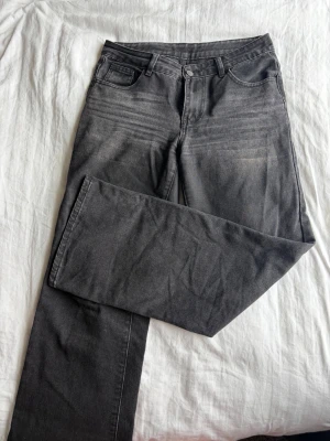 Grå raka jeans - Säljer ett par grå jeans med rak passform. Jeansen har normal midja och subtila slitningar framtill för en cool look. Perfekta till en avslappnad stil och lätta att matcha med det mesta. Materialet är mjukt denim i bomull.