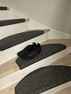 Svarta Adidas fotbollsskor - Säljer ett par helsvarta fotbollsskor från Adidas med klassisk låg profil och snörning. Skorna har dobbar för bra grepp på planen och är tillverkade i syntetmaterial som ger en lätt och smidig känsla. Perfekta för dig som vill ha stilrena och funktionella skor till matchen. Kommer med extra snöre!!!