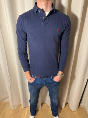 Marinblå Långarmad piké  - Hej! Nu säljer vi denna sjukt snygga Ralph Lauren långarmade piké tröjan för endast 325kr, nypris på den här badboyen ligger på cirka 1500kr💪Storlek S men passar M likabra! Skicket syns på bilderna och enligt vår bedömning 9/10! Hör av er vid frågor. Pris kan sänkas vid snabb och smidig affär💙 // studio II Resell 