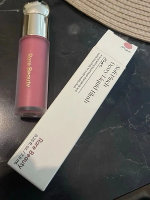Rare Beauty Soft Pinch Dewy Liquid Blush - Flytande rouge från Rare Beauty i nyansen 'Hope', en mjuk rosa färg. Kommer i en stilren, frostad flaska med silvrigt lock. Perfekt för att ge kinderna en fräsch och naturlig lyster. Enkel att applicera tack vare den smidiga applikatorn. Nypris 358kr